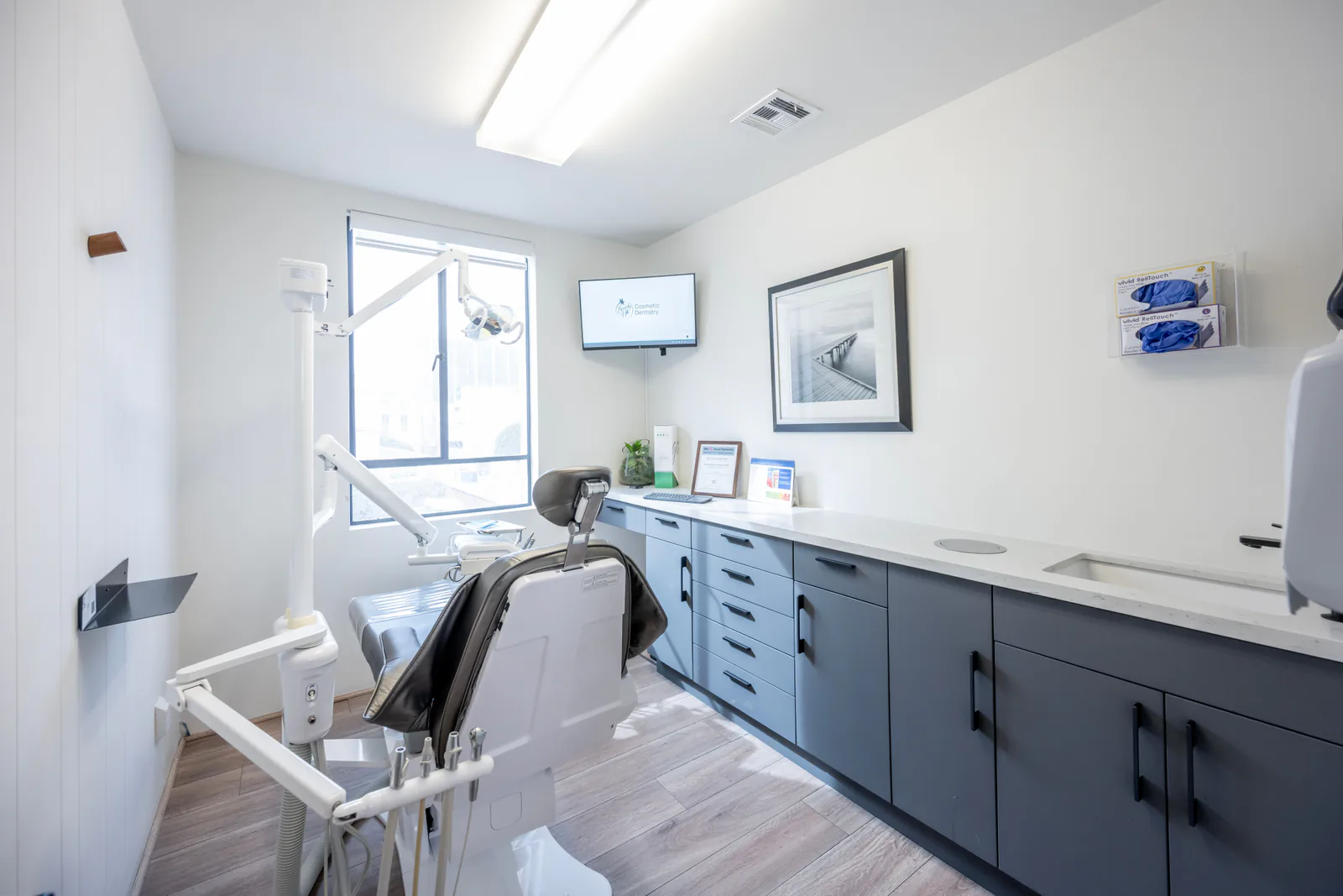 A bright dental treatment room with a chair and clinical equipment.