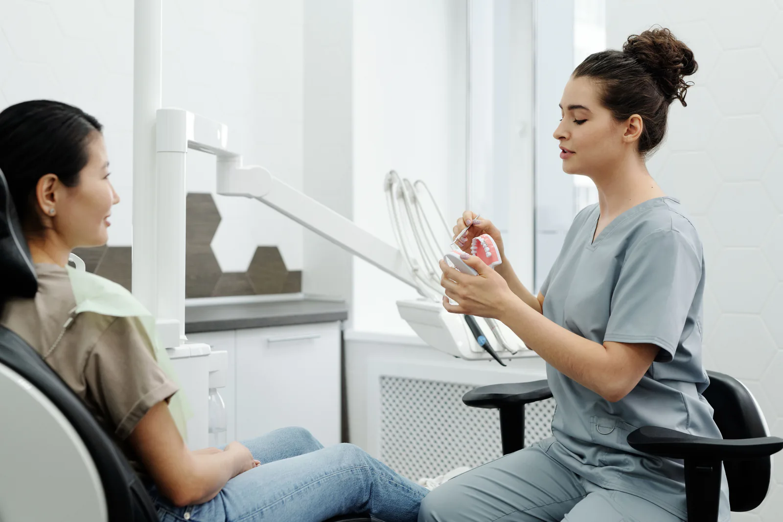 A professional presents a dental model during a clinical conversation.