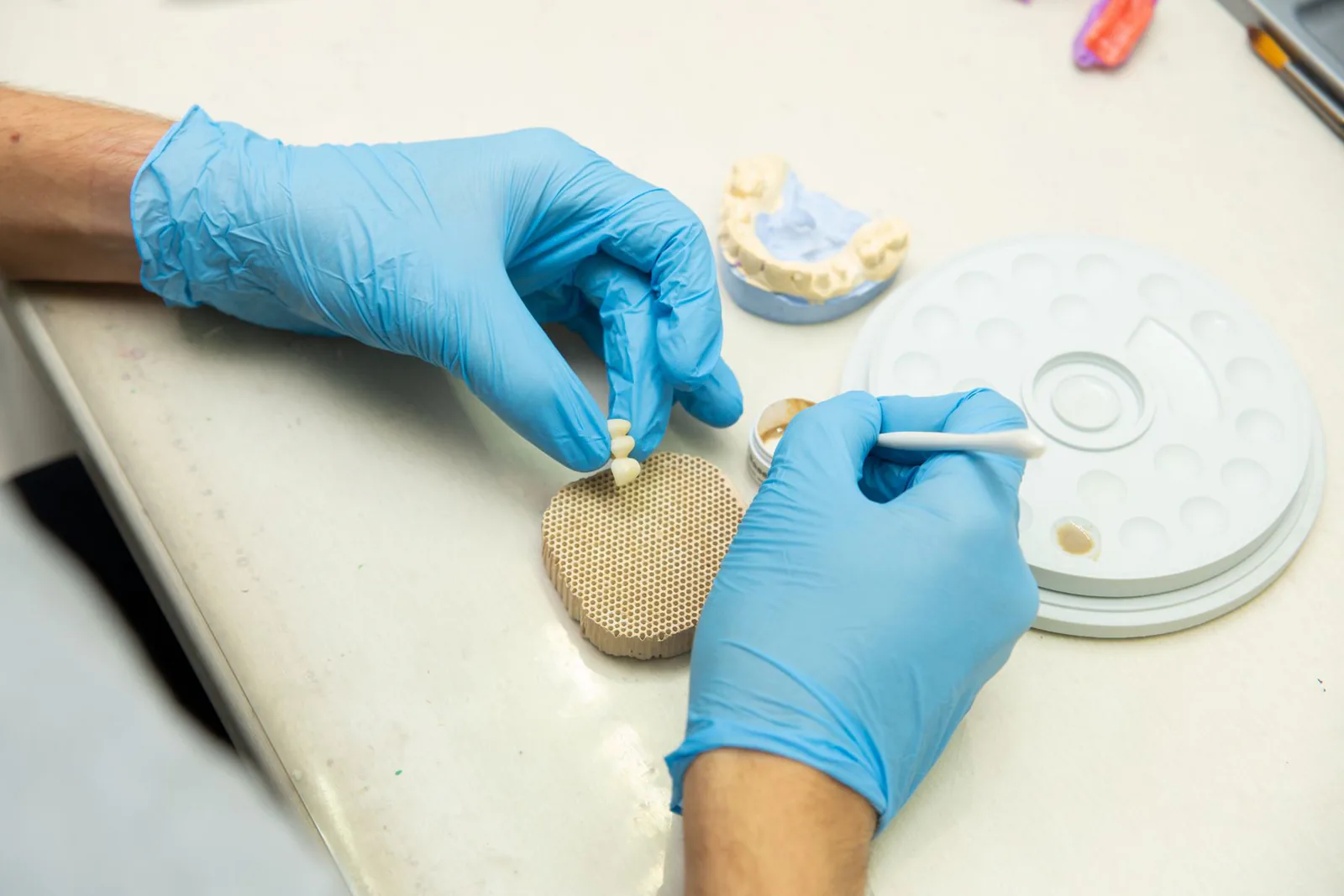Editorial image of hands working on a ceramic dental piece