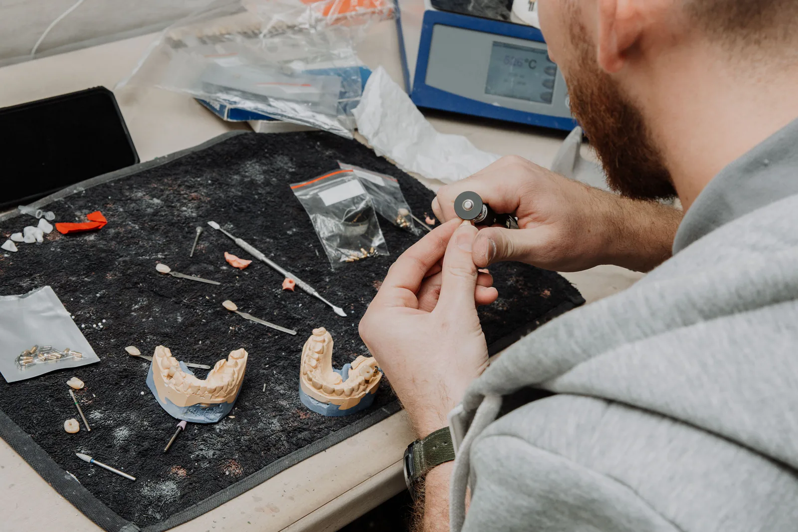 A technician works on a dental mould with precision instruments.